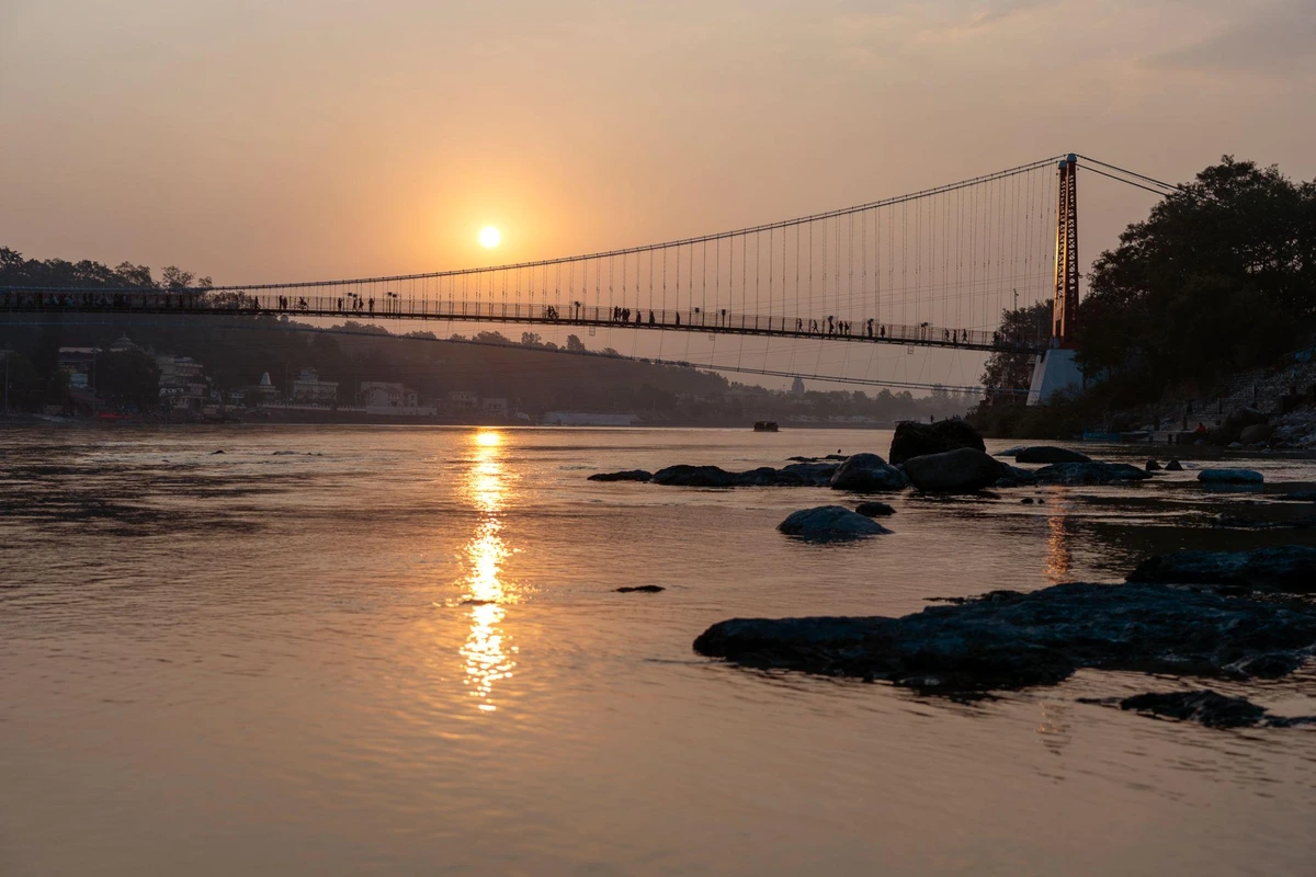 Ganges river embankment and bridge at sunset in Rishikesh
